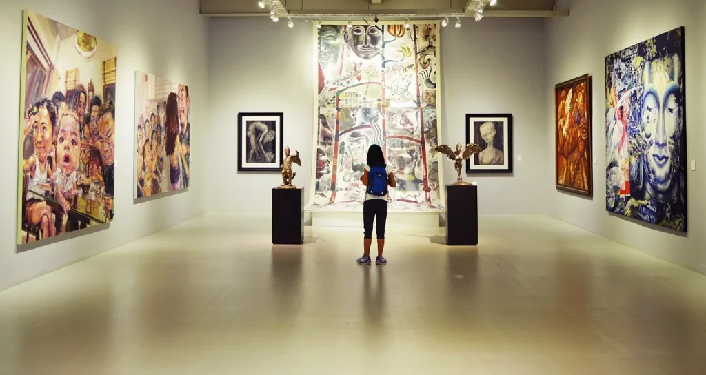 Image of a gallery in a museum with a young female child at the centre of the frame, facing away from the camera and towards a piece of art.