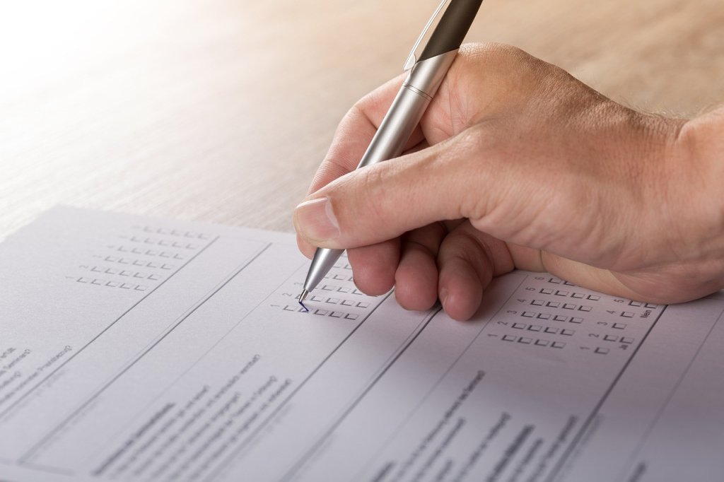 Image of hand holding a pen completing a questionnaire.