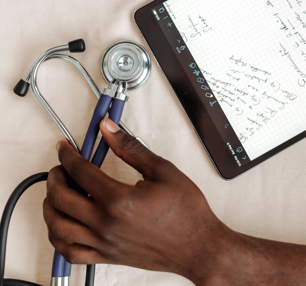Hand holding a stethoscope alongside notes.