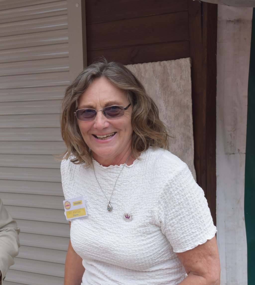Smiling middle aged lady with shoulder length light brown hair and a white top.